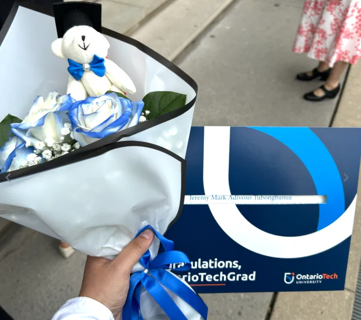 Holding my diploma and flowers with a bear